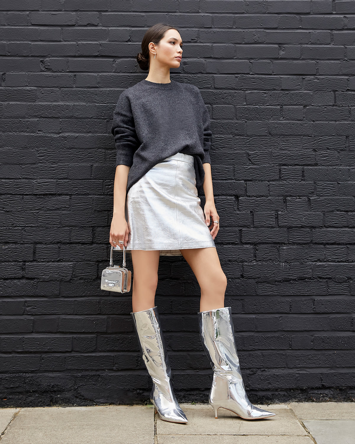 Model wearing Dune London Smooth silver knee high boots and Santerini silver bag