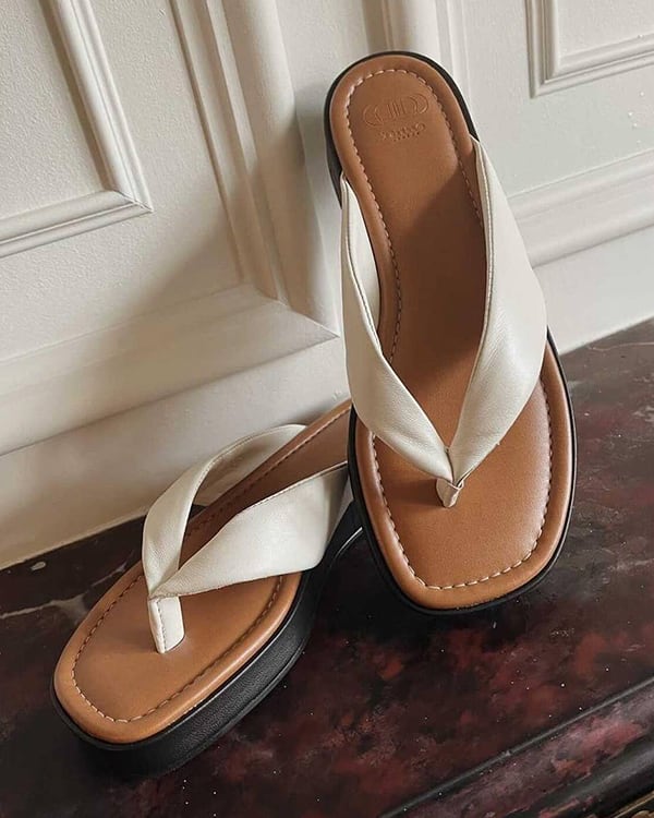 The Longisland sandals in white propped up against a wall