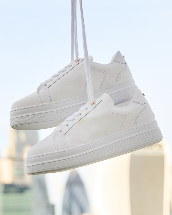 Women's white platform leather trainers with London skyline in the background