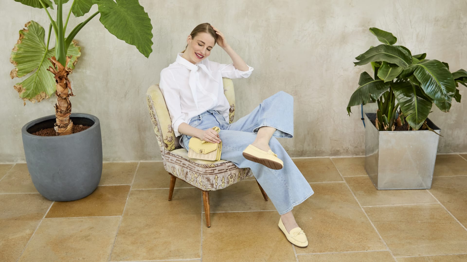 A women wearing yellow loafers and a yellow raffia bag.