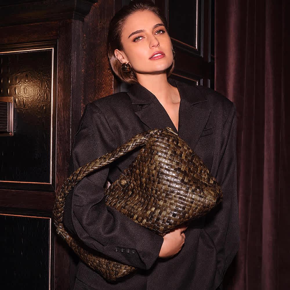 Woman holding khaki woven shoulder bag