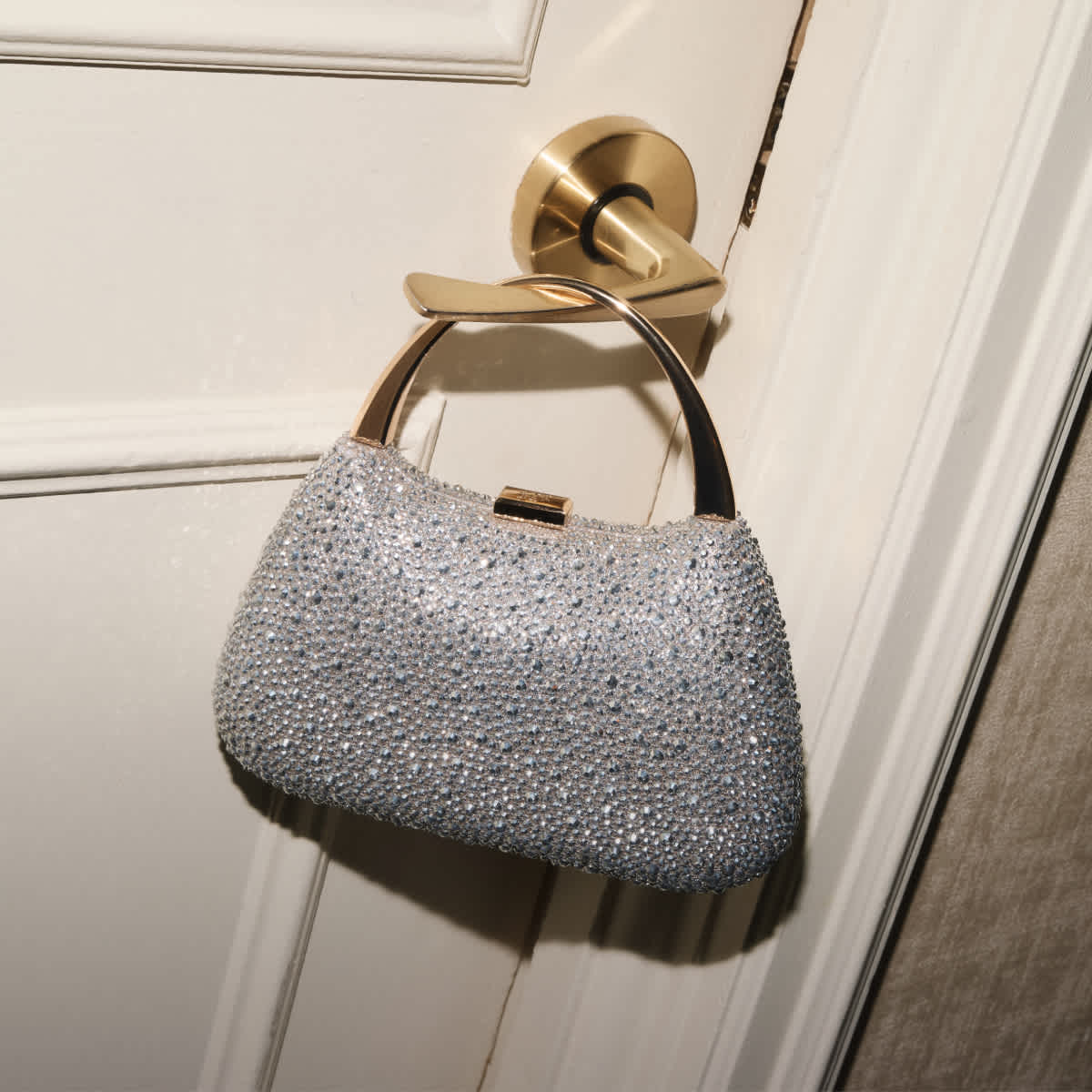 Gold handle embellished bag, hung on a door handle