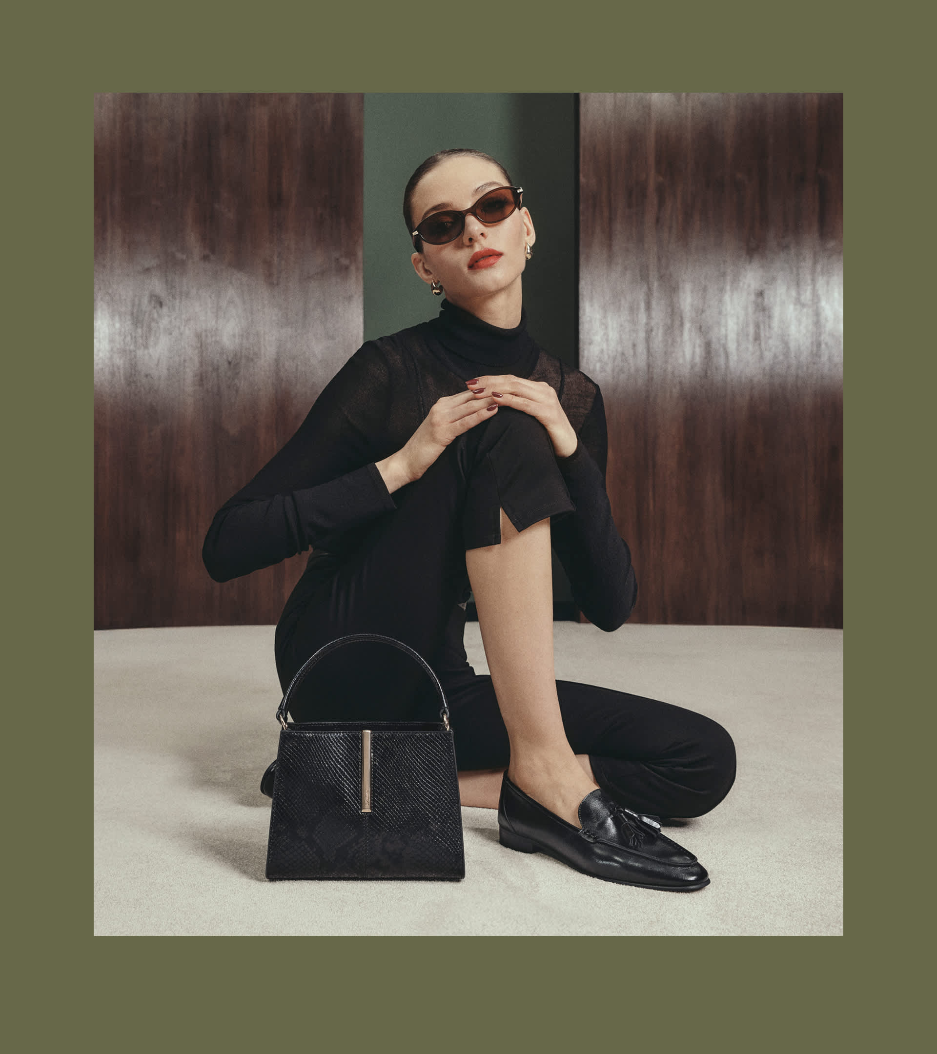 A woman sat on the floor wearing loafers with a dune london bag next to her 
