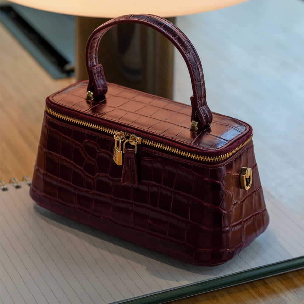 A burgundy Dune handbag on a table 