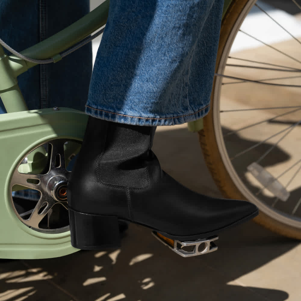 A woman on a bike wearing a black ankle boot