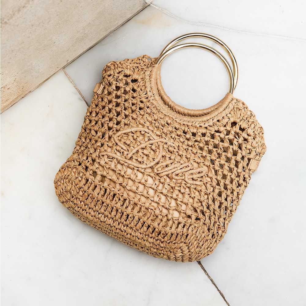 A raffia bag with Dune logo on the front and round metal handles