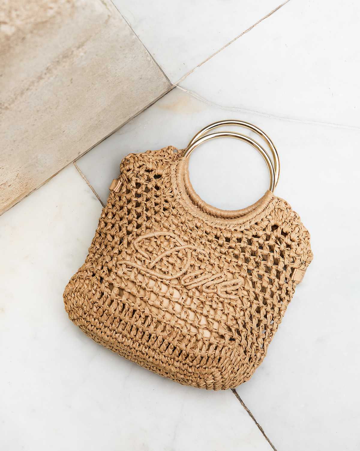 A raffia bag with Dune logo on the front and round metal handles