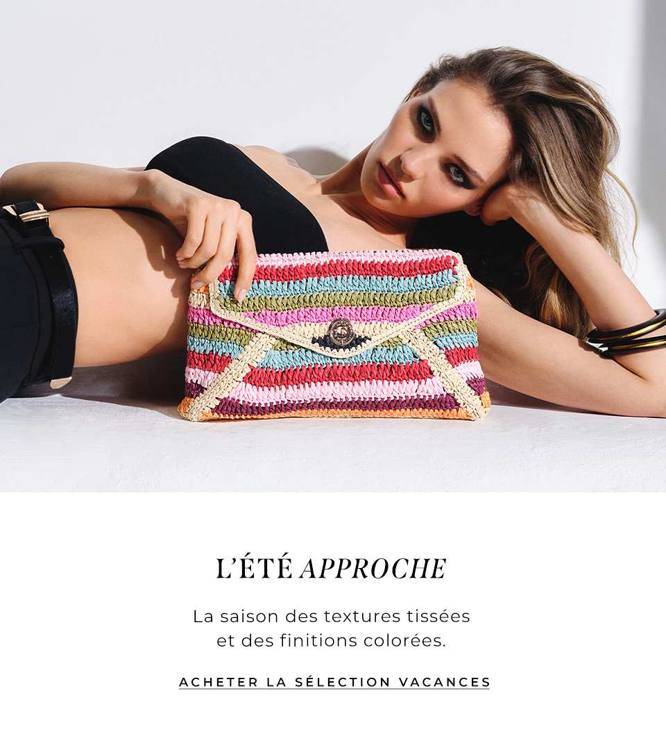 model laying down holding the essentials multicoloured stripe raffia clutch bag