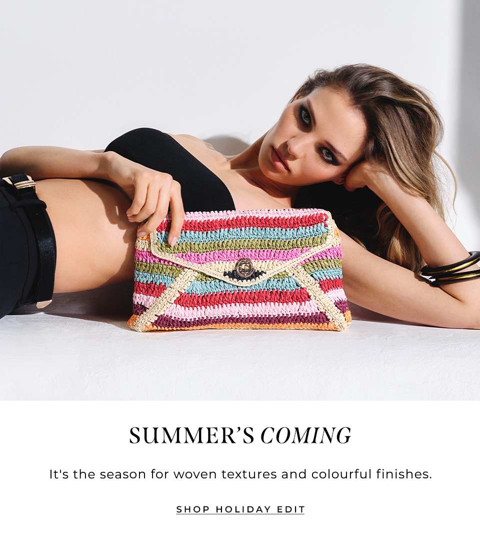 model laying down holding the essentials multicoloured stripe raffia clutch bag